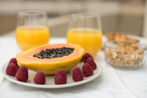 a plate of fruit and berries on a table with glasses of orange juice at BCharming House in Porto