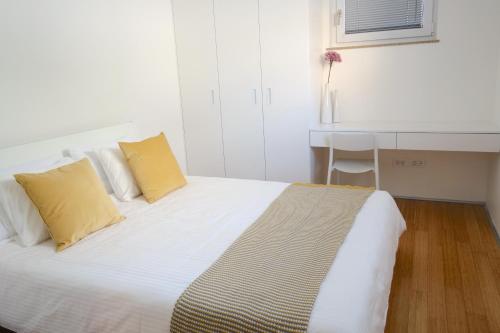 a white bed with two yellow pillows in a room at Sensei apartment in Ljubljana