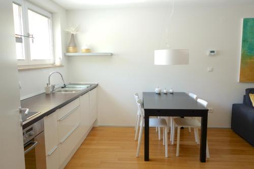 a kitchen with a black table and white cabinets at Sensei apartment in Ljubljana