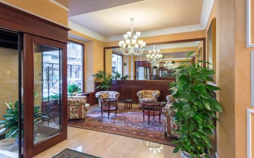a lobby with a table and chairs and plants at Hotel Minerva Palace in Montecatini Terme