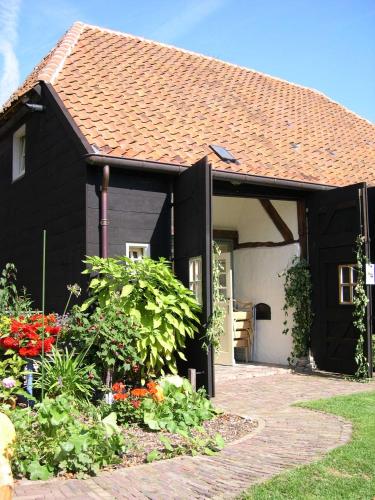 a black house with a garden in front of it at De Hopbel & Het Koevinkje in Liempde