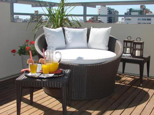 a wicker chair on a balcony with two tables with drinks at Zoom Apartments Hotel Boutique in Cordoba