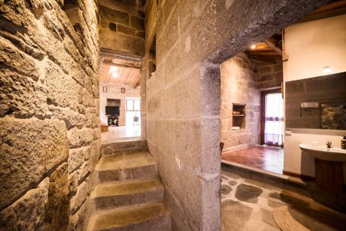 um corredor de pedra com uma parede de pedra e um lavatório em Aldea Rural Pazos De Arenteiro em Pazos de Arenteiro