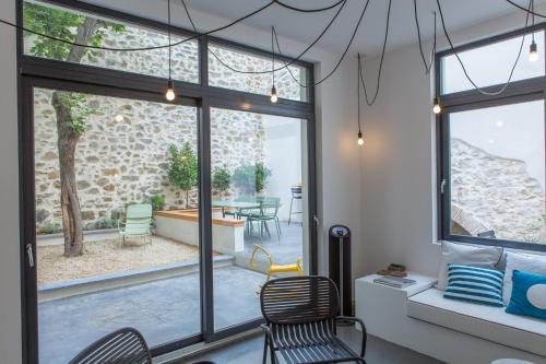 een kamer met ramen en stoelen en een patio bij La Maison des Vendangeurs sur Mer in Gruissan