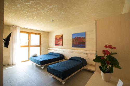 - une chambre avec deux lits et une plante en pot dans l'établissement Cave Bianche Hotel, à Favignana