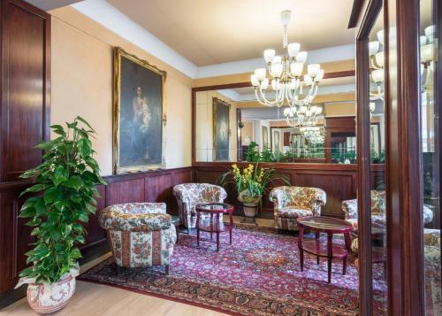 a lobby with chairs and a table and a mirror at Hotel Minerva Palace in Montecatini Terme