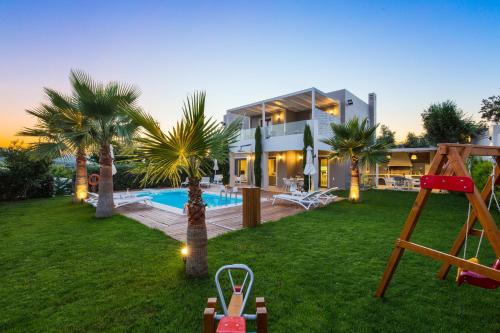 a house with a yard with a pool and palm trees at Aria Villas, modern paradise, By ThinkVilla in Pigi