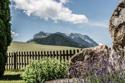 a fence with purple flowers and mountains in the background at Hotel Riedl in Kössen