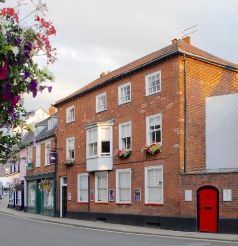 a brick building with a red door on a street at Short Stay Bungay in Bungay