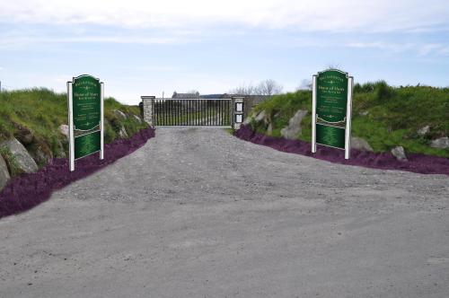 a gate with two green signs on the side of a road at The Barn at Ballaloaghtan in Ballasalla