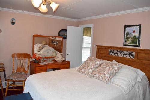 a bedroom with a bed and a desk with a mirror at The Spaniards Room Heritage Home in Spaniards Bay