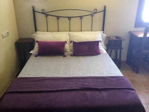 a bedroom with a large bed with two purple pillows at Hostal San Pedro in Cuenca