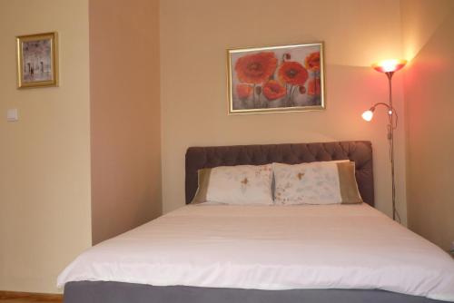 Apartament Planty في زاموسك: غرفة نوم بسرير مع شراشف بيضاء ومصباح