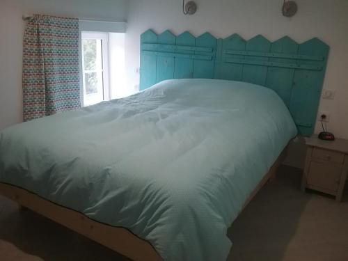 a large bed with a blue headboard in a bedroom at Cottage B2 Bazenville in Bazenville