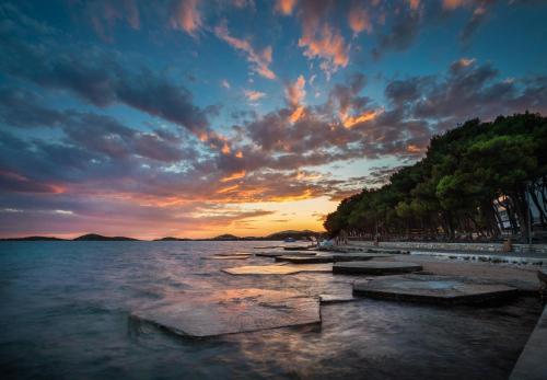 a sunset over a body of water with trees at Villas Arausana & Antonina in Vodice