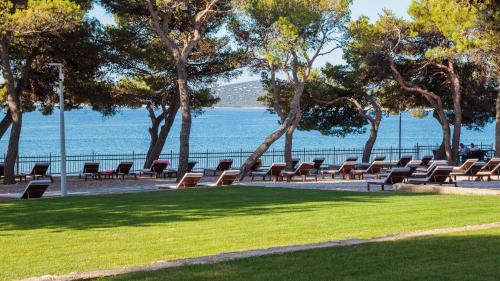 a row of chairs in a park next to the water at Villas Arausana & Antonina in Vodice
