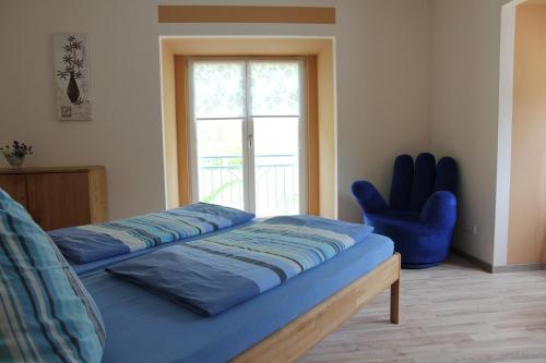 ein Schlafzimmer mit einem Bett und einem blauen Stuhl in der Unterkunft Cafe Klering in Briedern