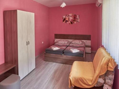 een slaapkamer met roze muren en een bed en een stoel bij АПАРТАМЕНТ ЗА ГОСТИ "Момчил'' in Sofia