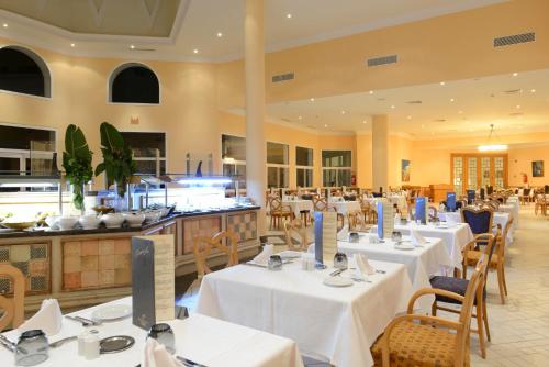 a restaurant with white tables and chairs and a kitchen at Vincci Saphir Palace & Spa in Hammamet