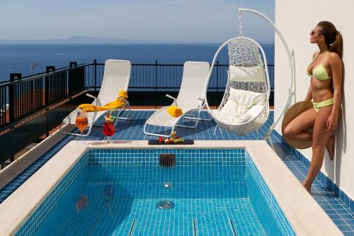 a woman in a bikini sitting next to a swimming pool at Hotel Continental in Sorrento