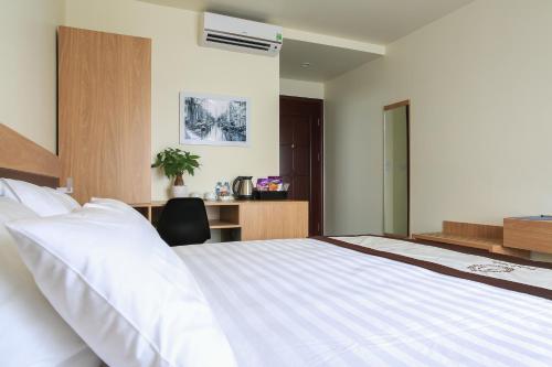 a bedroom with a large white bed and a desk at Punt Hotel in Hai Phong