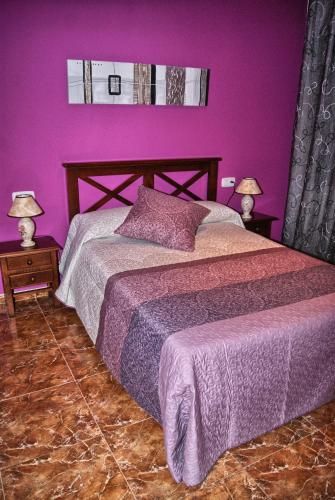 a purple bedroom with a bed and two lamps at Casa Rural Buenaventura in Fermoselle
