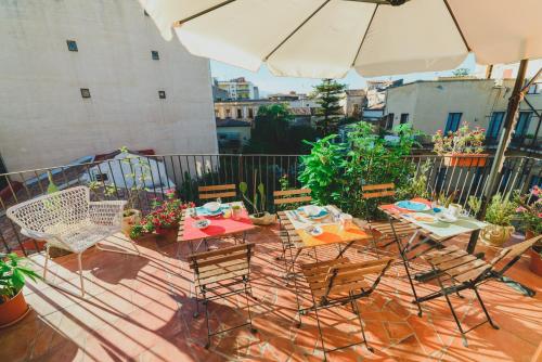 patio con tavolo, sedie e ombrellone di Bellini Home B&B a Catania