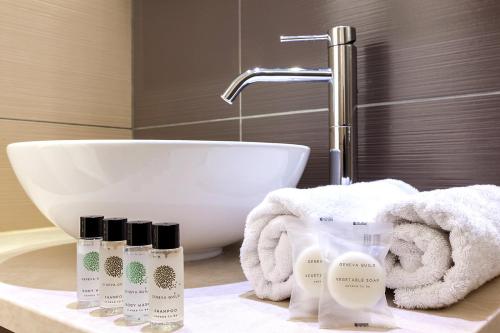 a bathroom with a sink and four bottles of soap at Memories Beach Hotel in Monolithos