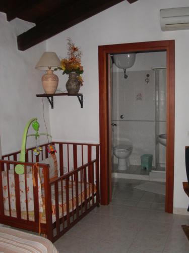 a room with a crib and a bathroom with a toilet at Locanda La Rosa in Pauli Arbarei