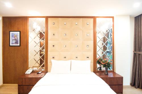 a bedroom with a large white bed and glass doors at Canary Ha Noi Hotel in Hanoi