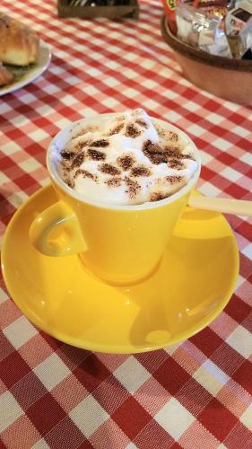 a cup of coffee sitting on a yellow plate on a table at La Casa Delle Rondini in Roncoferraro