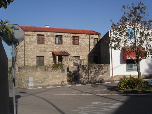 an old brick building with a tree in front of it at Locanda La Rosa in Pauli Arbarei
