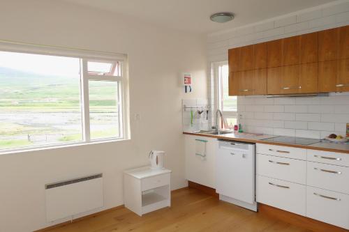 a kitchen with white cabinets and a large window at Thorbrandsstadir Farm Holidays in Þorbrandsstaðir