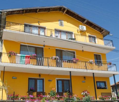a yellow apartment building with balconies and flowers at Morski Rai Rooms in Byala