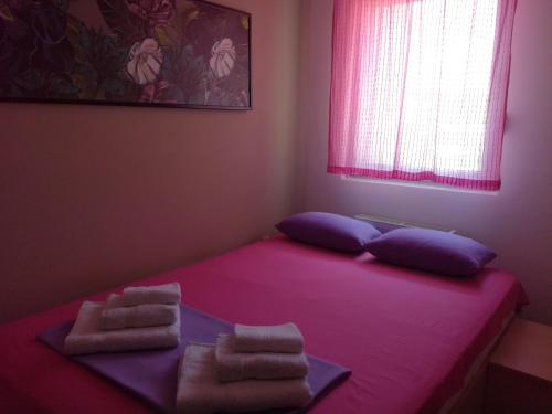 a bedroom with a pink bed with towels on it at Naissa Apartment in Niš