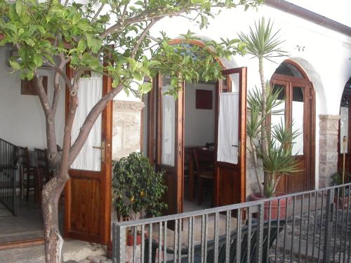 a house with wooden doors and a tree at Locanda La Rosa in Pauli Arbarei