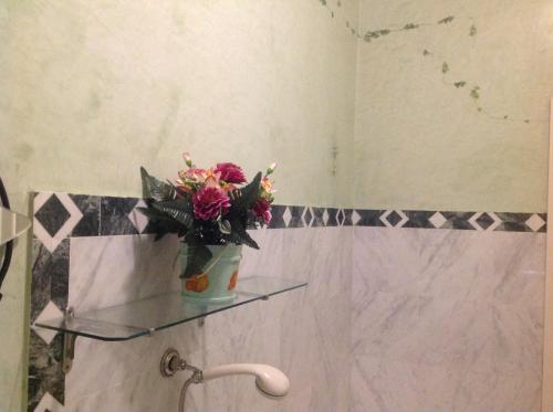 a glass shelf in a bathroom with a vase of flowers at La Vecchia Quercia in Pergine Valdarno