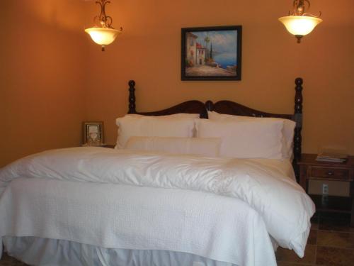 Spanish Villa Inn في سانت هيلينا: غرفة نوم بسرير وملاءات بيضاء واضاءات