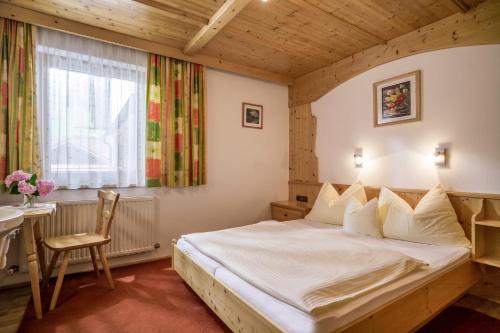 a bedroom with a bed and a table and a window at Anja's Schönblick - Bed & Breakfast in Gerlos