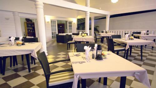 a restaurant with white tables and chairs and a checkered floor at David's Beach Hotel in Union Island