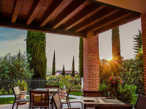 a patio with tables and chairs under a wooden pergola at Hotel Relais Agli Olivi in Lazise
