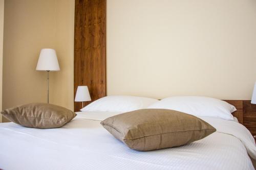 a white bed with two pillows on top of it at Villa Rooms Mediteran in Borovići