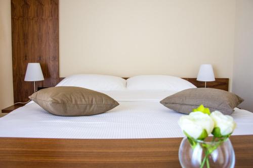 a bed with two pillows and a vase with flowers at Villa Rooms Mediteran in Borovići
