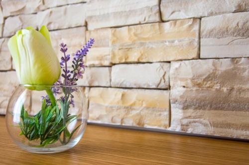 a vase with flowers in it on a table at Villa Rooms Mediteran in Borovići
