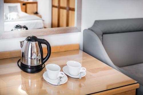 a tea kettle and two cups on a table at Hotel Bellavista in Lignano Sabbiadoro