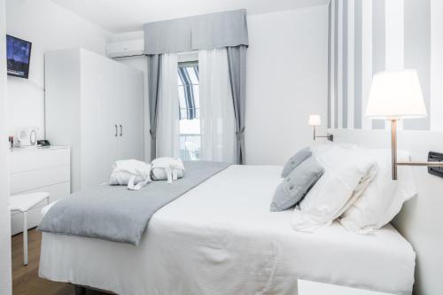 a white bedroom with a bed with two stuffed animals on it at Hotel Bellavista in Lignano Sabbiadoro