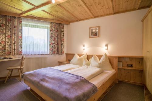 a bedroom with a bed and a desk and a window at Anja's Schönblick - Bed & Breakfast in Gerlos