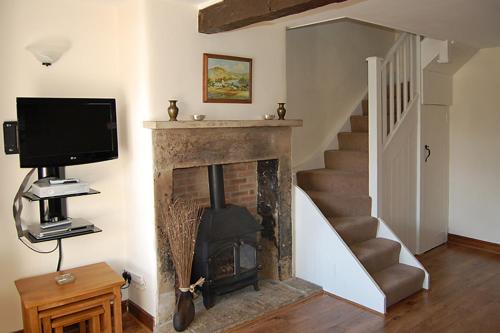 a living room with a fireplace and a television at May Cottage in Tideswell