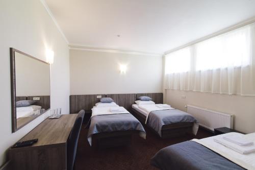 a room with three beds and a table and a mirror at Zinedine Sport-Hotel in Uzhhorod
