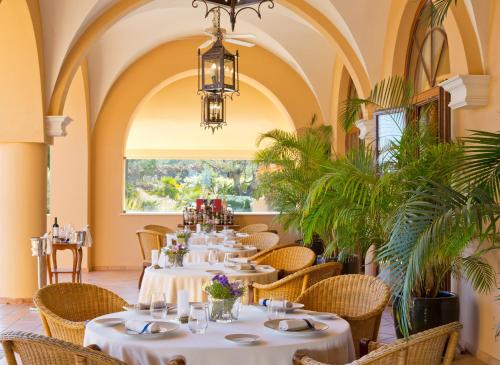 a dining room with tables and chairs and a chandelier at Monte Rei Golf & Country Club in Vila Nova de Cacela